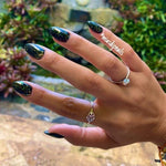Black stiletto nails with multicolor chameleon flakes creating a shimmering effect.