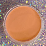 Round container of smooth, matte peach-orange dip powder for nails.