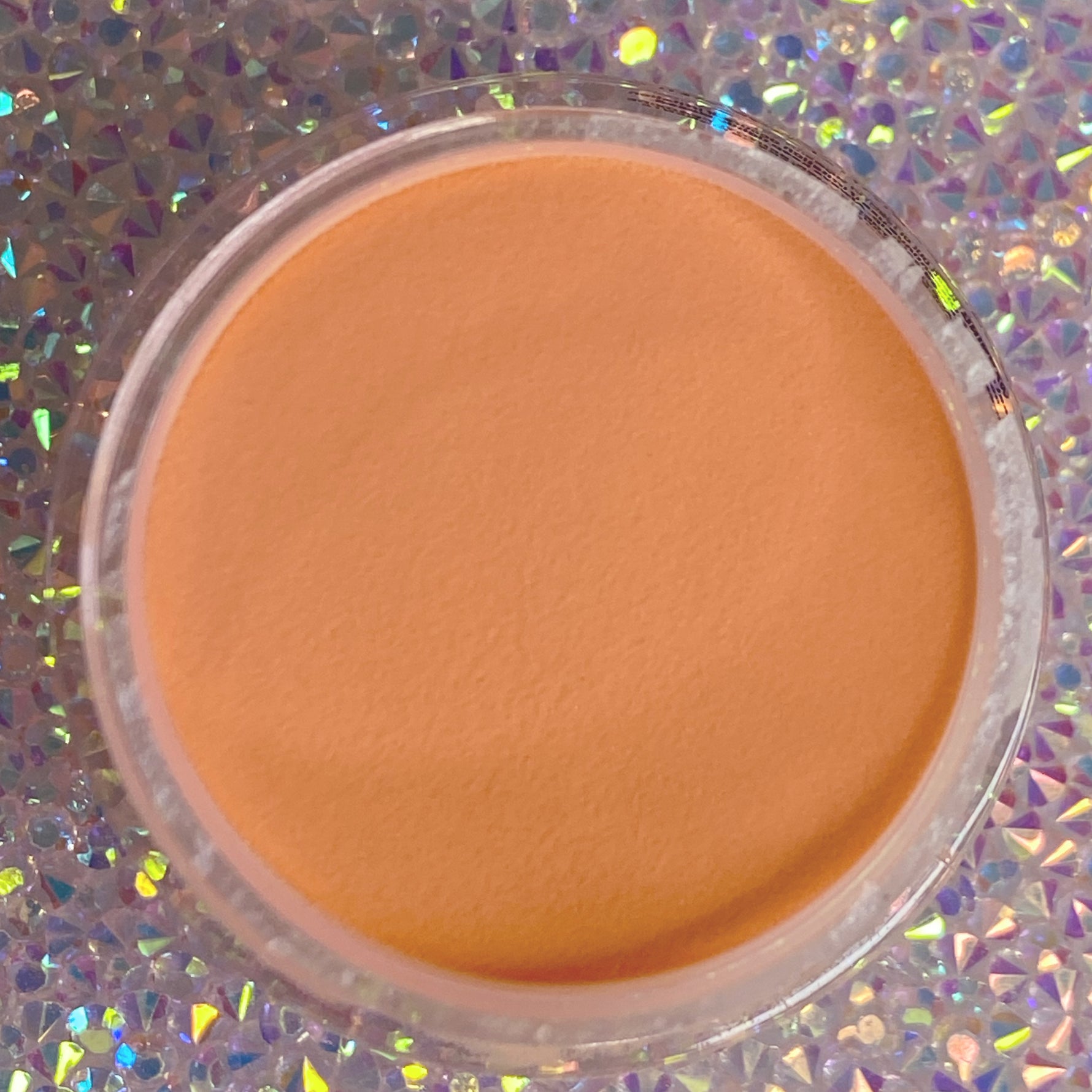 Round container of smooth, matte peach-orange dip powder for nails.