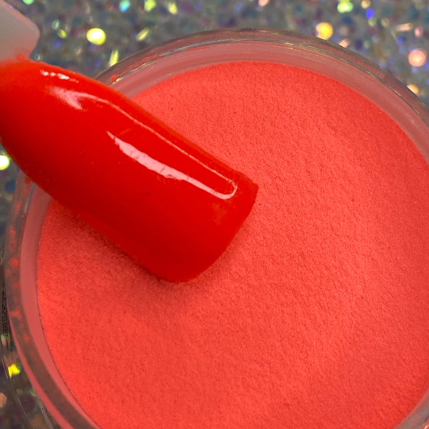 Bright neon orange glow-in-the-dark dip powder with matching glossy swatch stick.