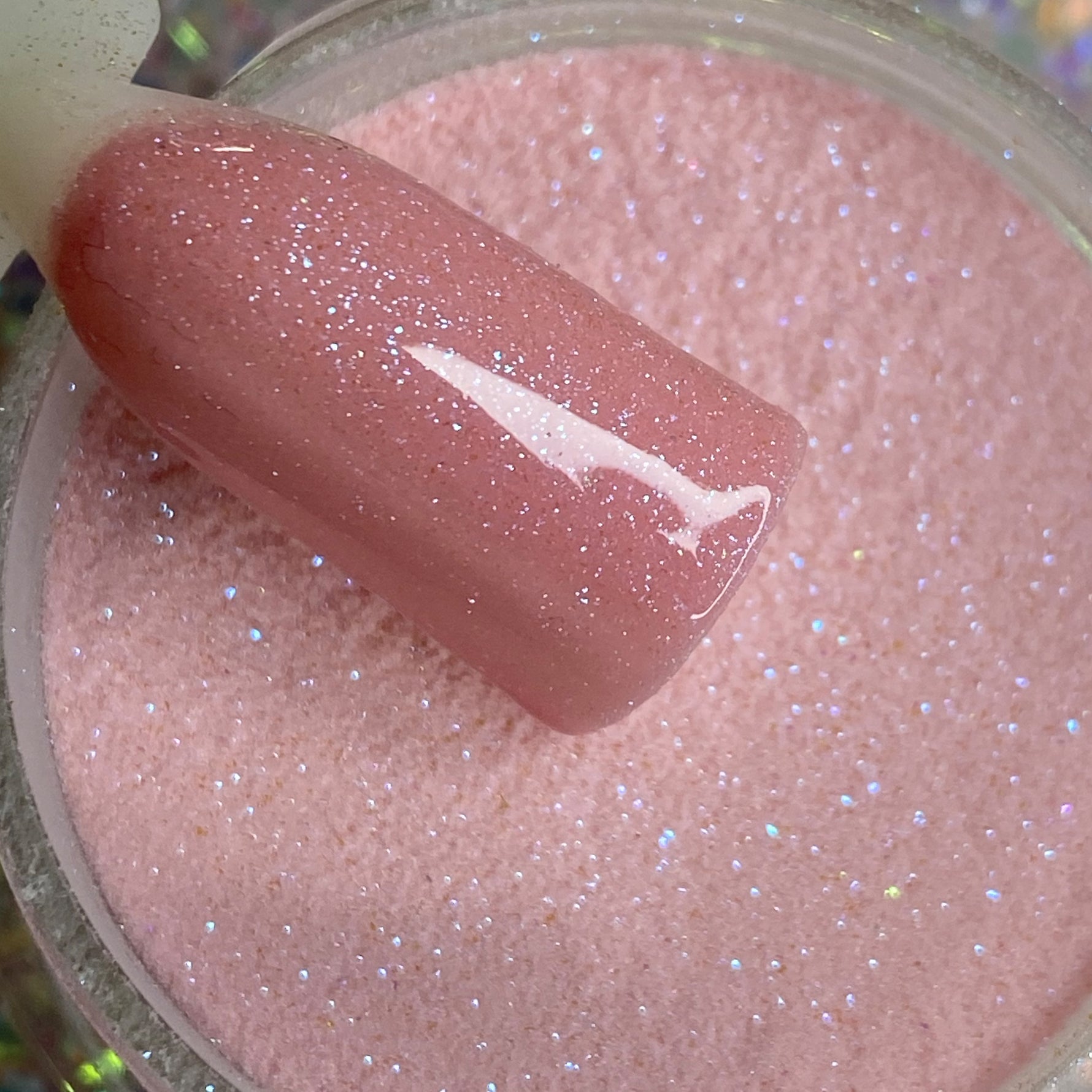 Light pink fine glitter dip powder with shimmering sparkle and glossy finish on nail tip.