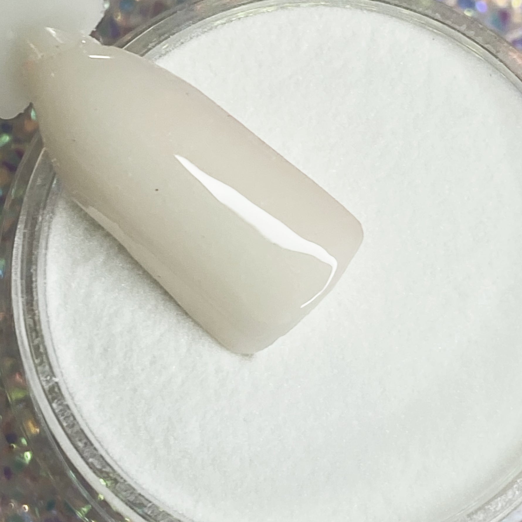Milky white solid dip powder with glossy finish on nail tip, glows blue in the dark.