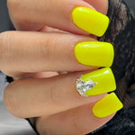 Bright neon yellow square acrylic nails with a rhinestone cluster accent on the ring finger.