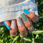 Matte bright blue, soft pink, chunky multicolor glitter, and chunky gold glitter nail powders on manicured nails.