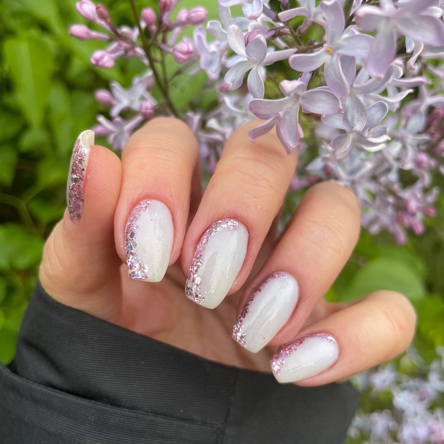 Long coffin nails with white glow-in-the-dark polish and silver glitter accents on pinky and ring fingers.