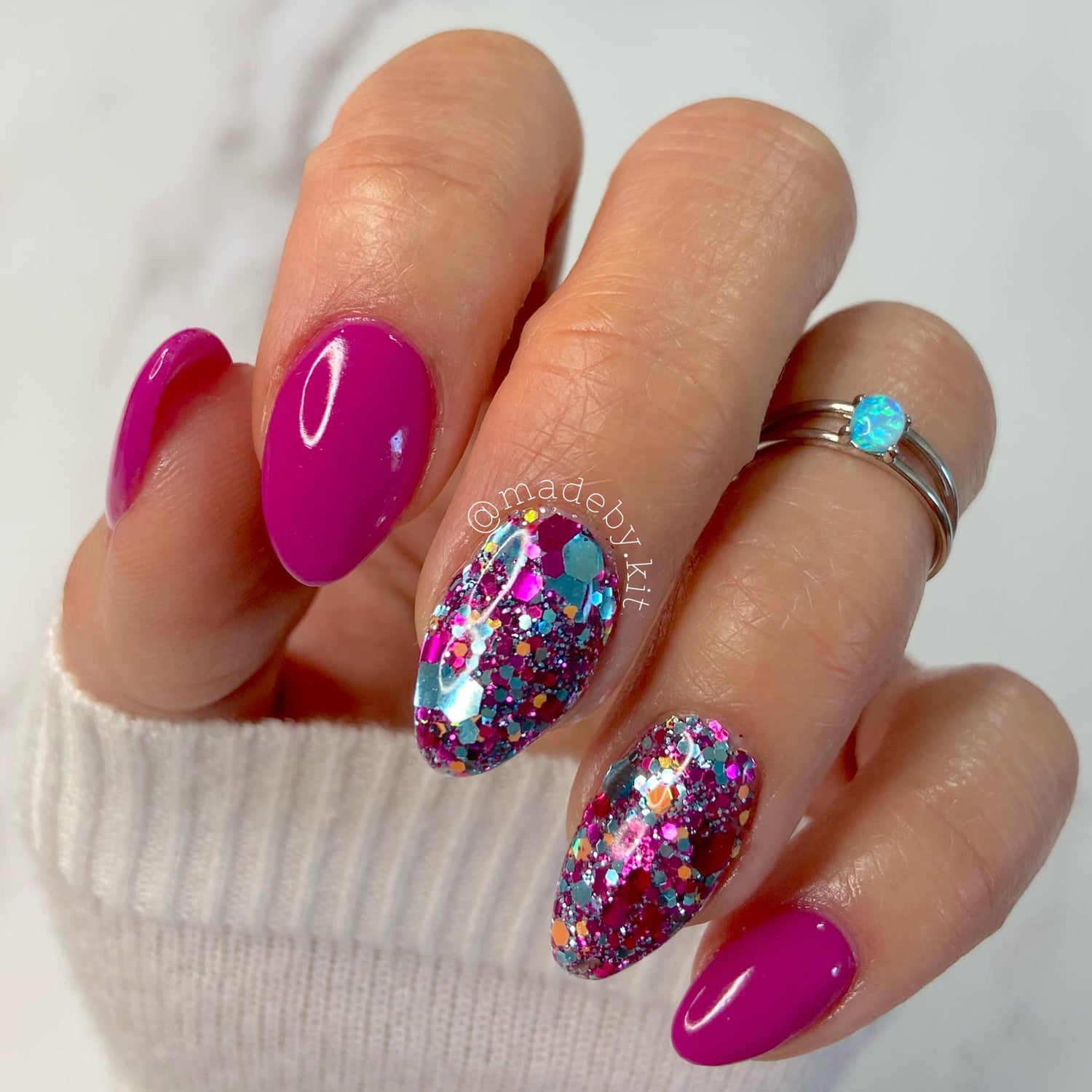 Bright hot pink solid dip powder nails with glitter accent nails in purple and blue tones.