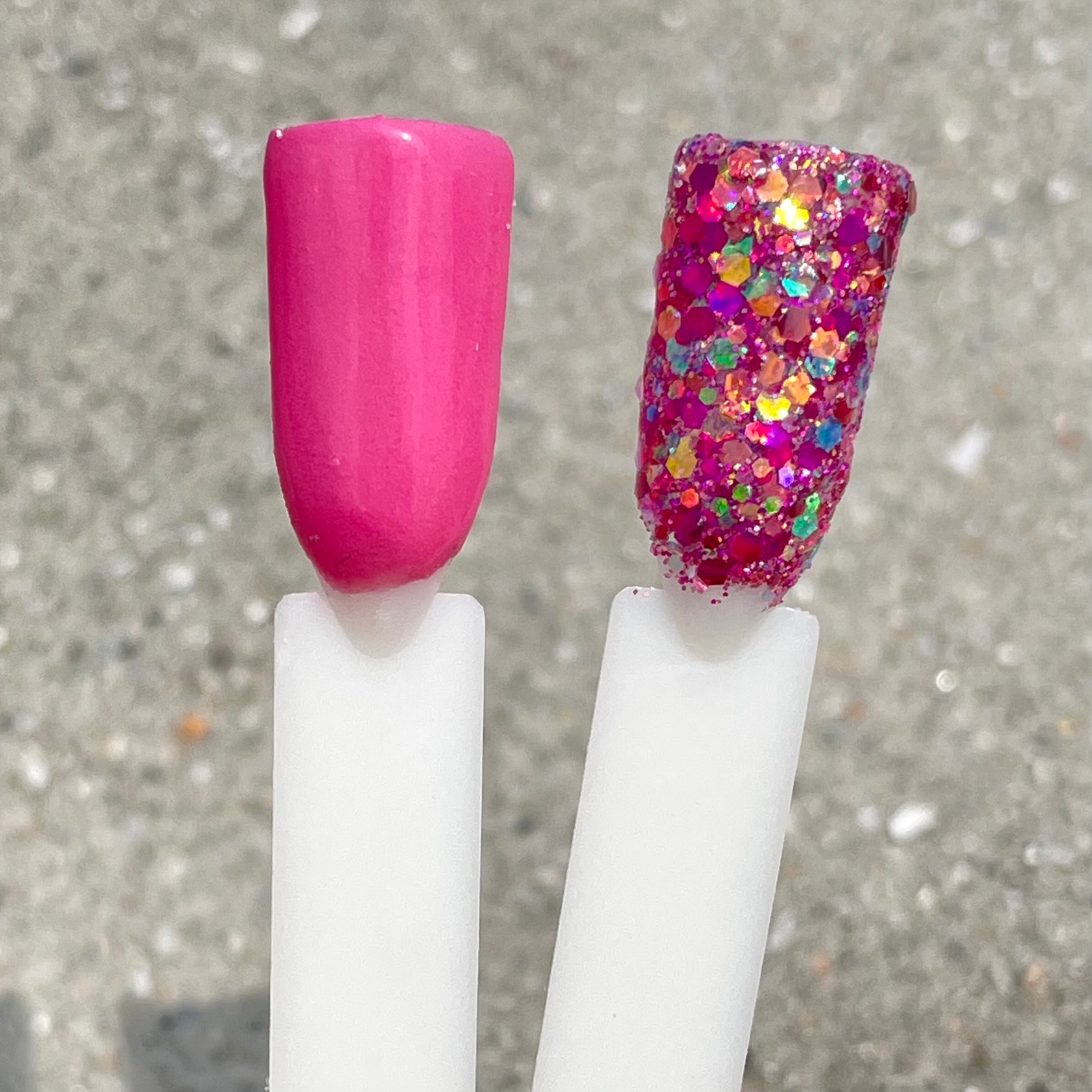 Bright pink solid dip powder next to bright pink glittery dip powder with multicolored hexagonal flakes.