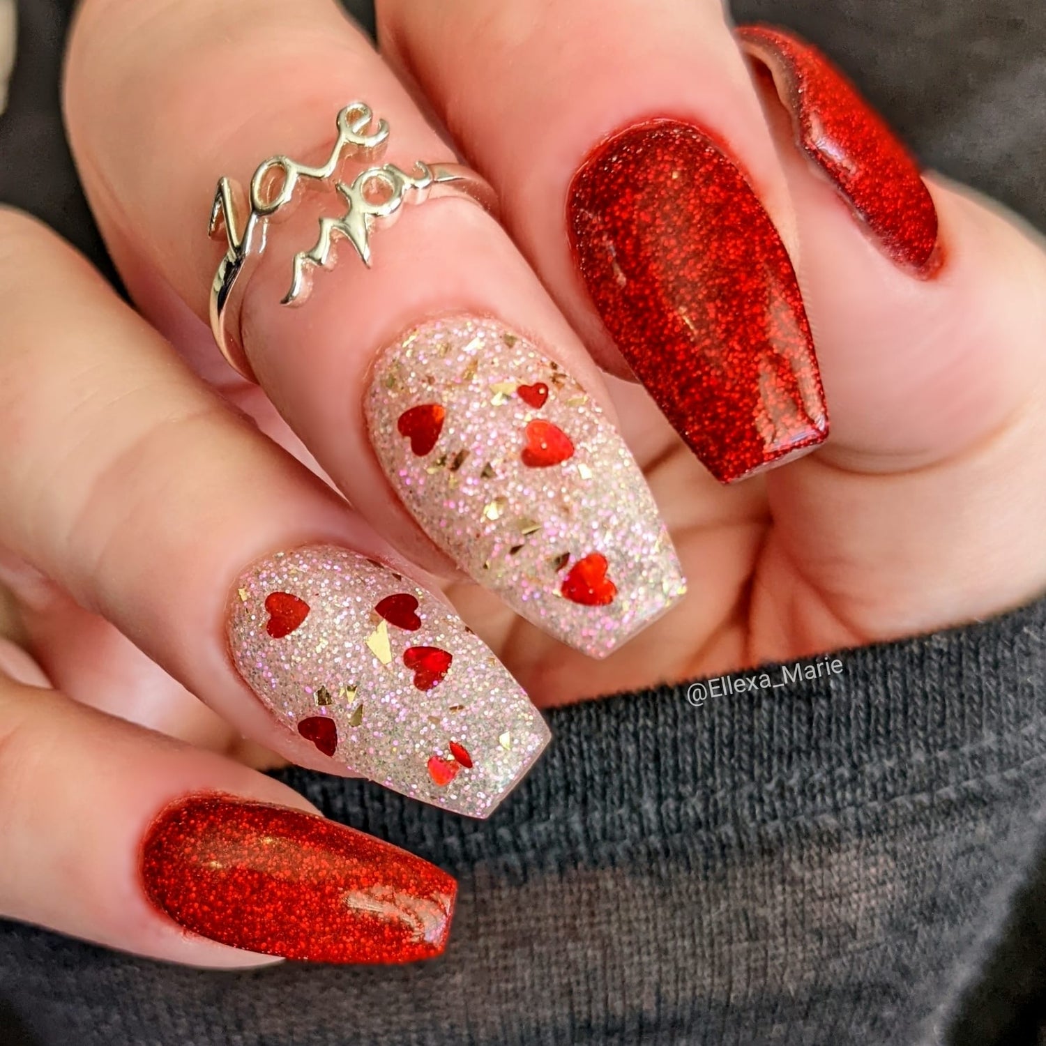 Red chrome glitter nails with accent nails featuring clear base and small red heart glitter designs.