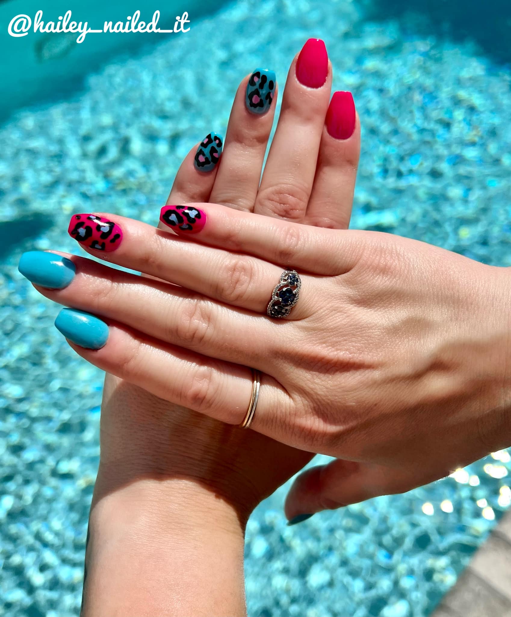Bright blue solid dip powder nails paired with glossy hot pink nails and black leopard print accent nails.
