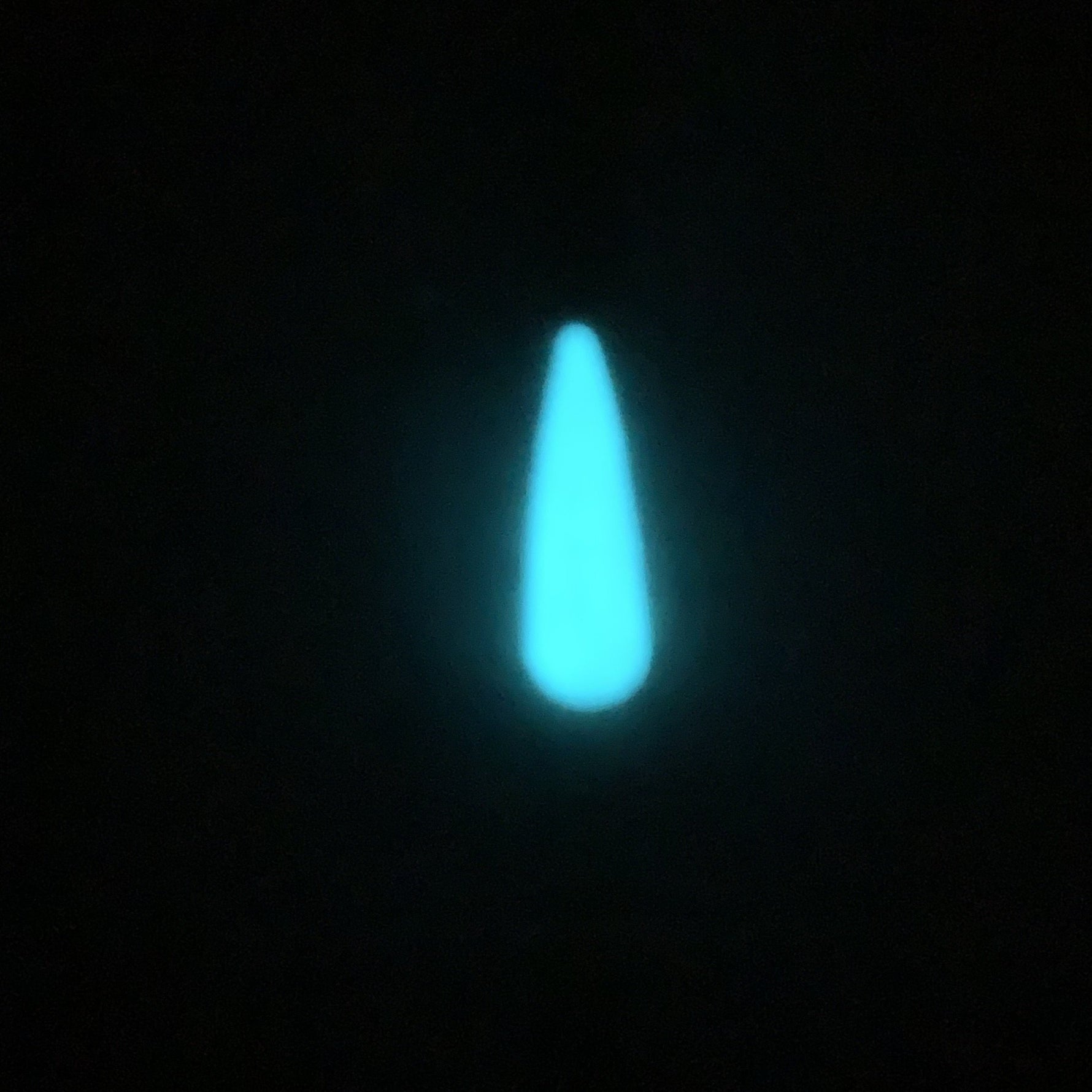 Glowing teardrop-shaped nail tip in bright white-blue glow against black background.