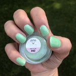 Mint green shimmer dip powder on nails with a jar labeled 