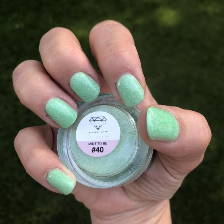 Mint green shimmer dip powder on nails with a jar labeled 