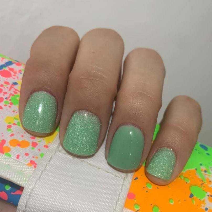 Mint green dip powder nails with fine shimmer and glitter on natural nails.