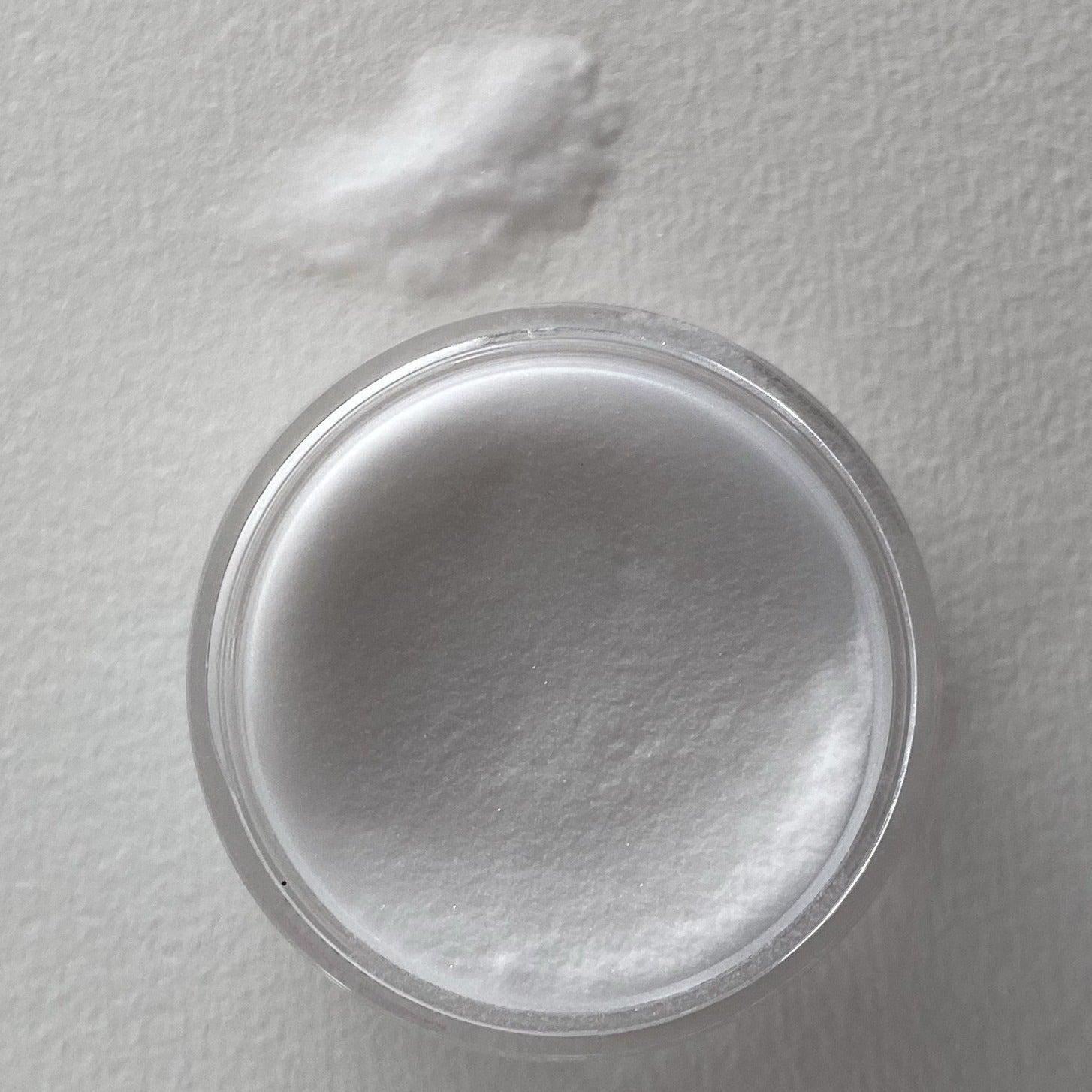 Clear jar filled with fine white glow-in-the-dark dip powder labeled DP V02 Full Moon with a small pile of loose powder.