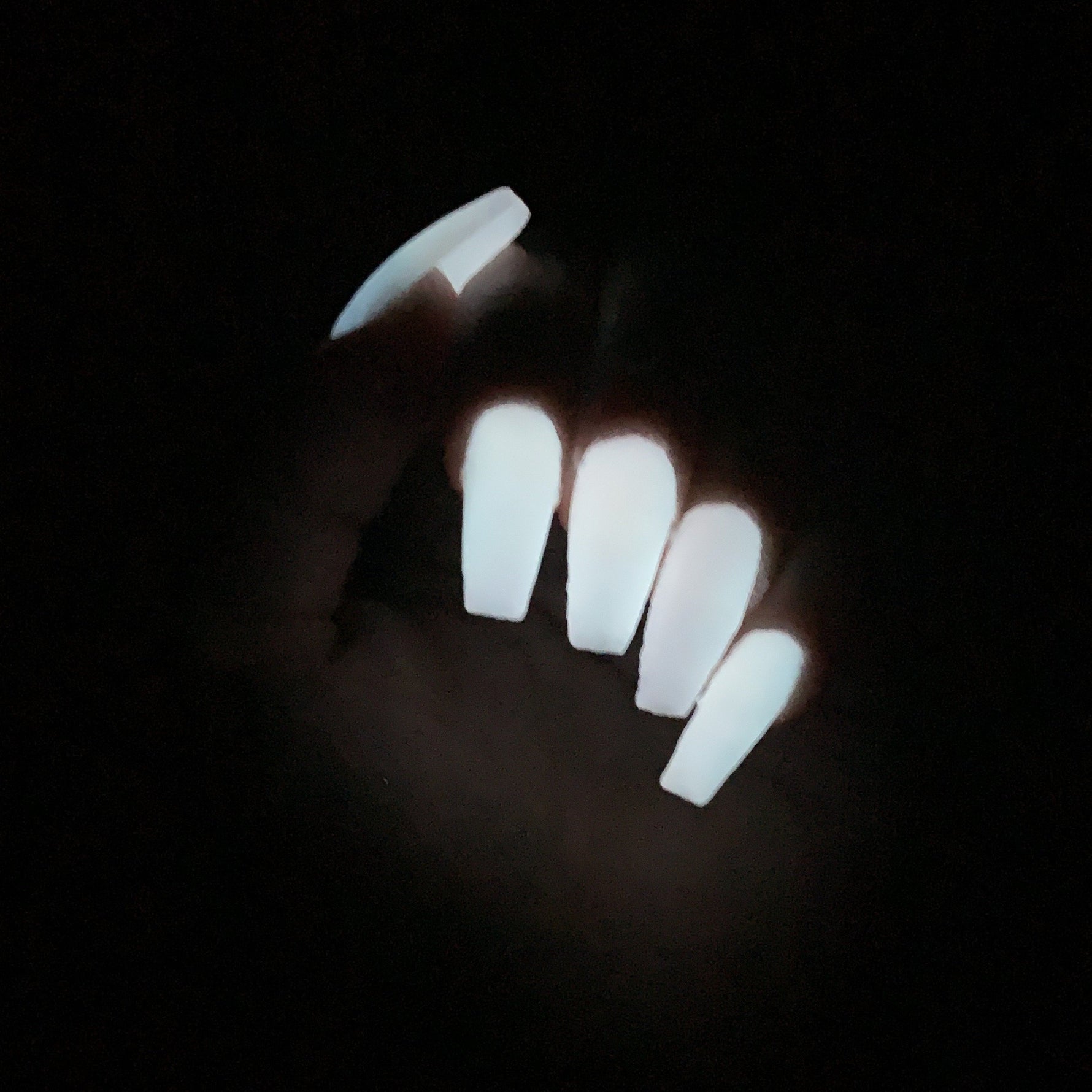Long coffin-shaped nails glowing bright white in the dark with a smooth, solid finish.