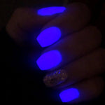 Purple glowing nails with one glittery gold accent nail under blacklight.