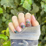 Short pink nails with multicolor chunky glitter dip powder accents on the ring and middle fingers.