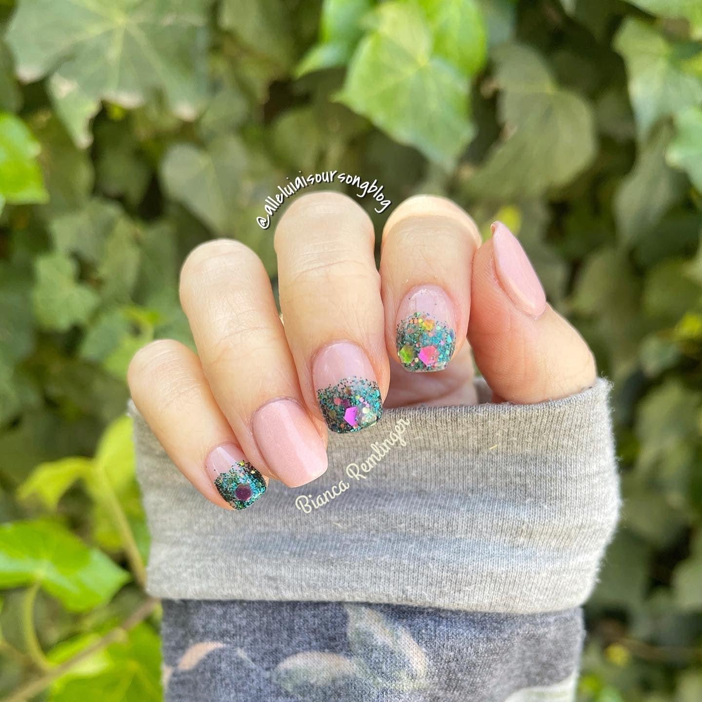 Short pink nails with multicolor chunky glitter dip powder accents on the ring and middle fingers.